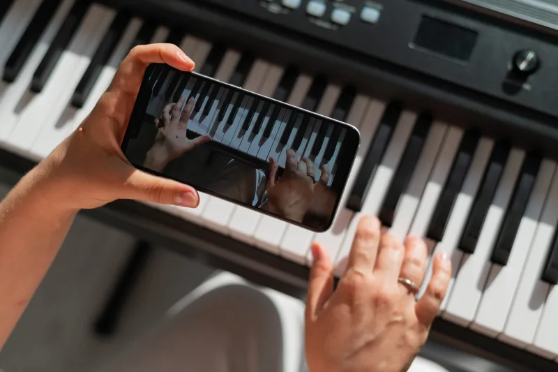 Un téléphone tenu au-dessus d’un clavier, une application de piano ouverte