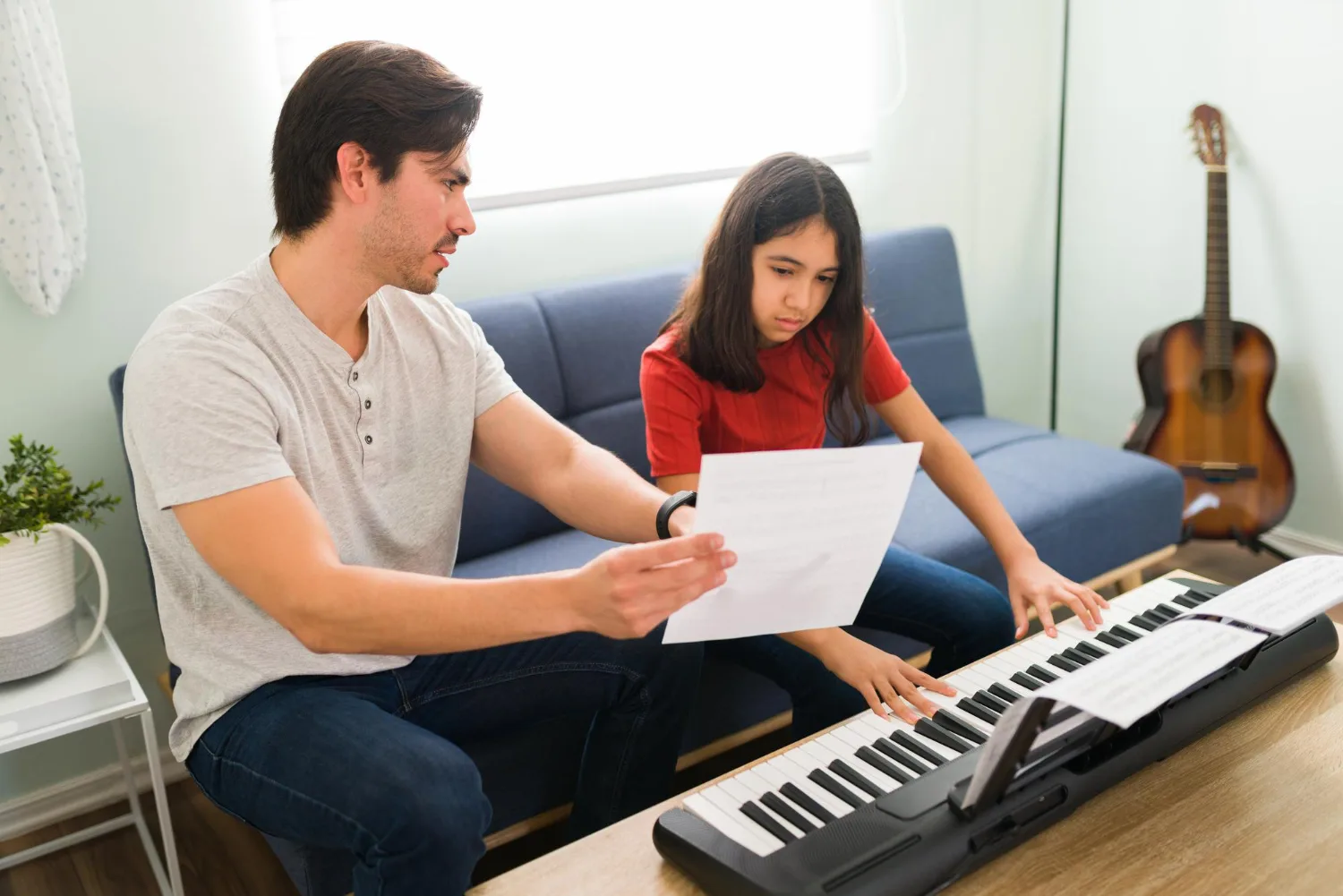 Un père et sa fille déchiffrent une partition devant un clavier