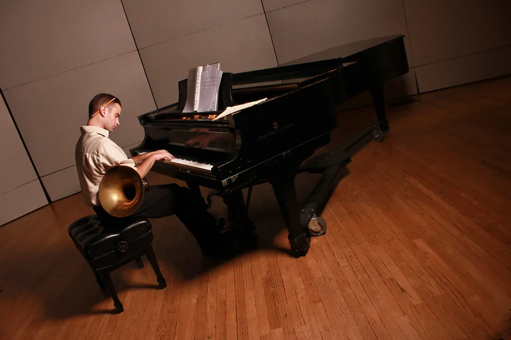 Un pianiste joue sur un piano à queue dans une salle aux murs clairs